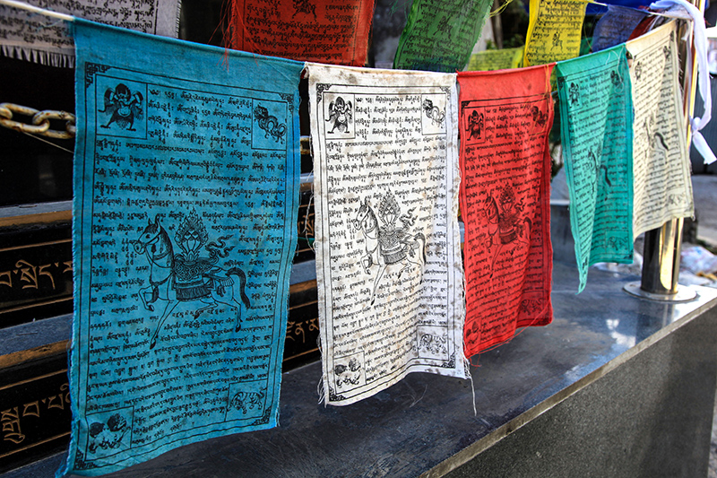 Prayer flags A couple of colorful Buddhist prayer flags hanging on a string. These are Lung ta style meaning they are hanging horizontal. Text and pattern clearly visible. Prayer flags are used to promote peace, compassion, strength, and wisdom.